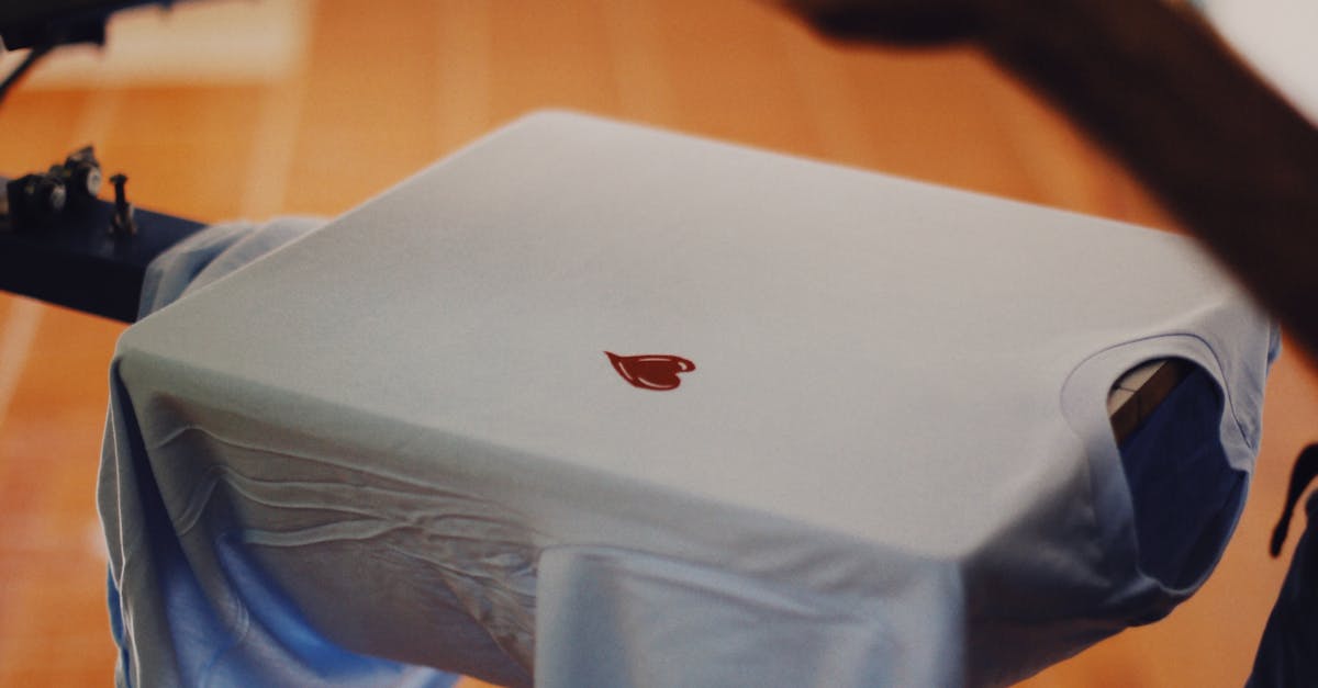 Close-up of a man using a T-shirt printing machine indoors.